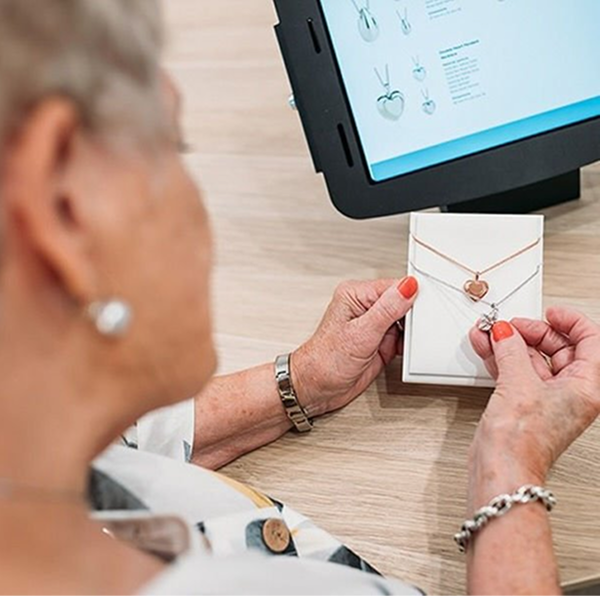 a woman holding and looking down at a cherished necklace